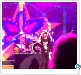 Ringo Starr trying on the hat tossed up to him onstage by Dr. Bob Hieronimus.